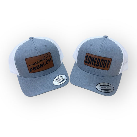Two Heather Gray and White Horizon Hat Co. trucker hats with SOMEBODY and Somebody's PROBLEM Rawhide patches