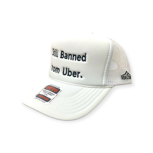 Angled view of Still Banned From Uber embroidered cap by Horizon Hat Co. in white/black lettering showing the bill and side panels