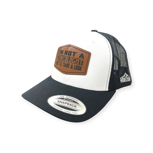 Angled view of Not A Gynecologist patch hat by Horizon Hat Co. in white/black showing the curved bill and side panels