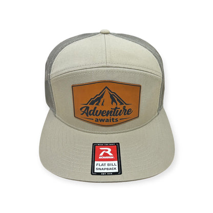 Front view of Adventure Awaits patch hat by Horizon Hat Co. in pale khaki/loden green showing adventure awaits patch with mountain artwork