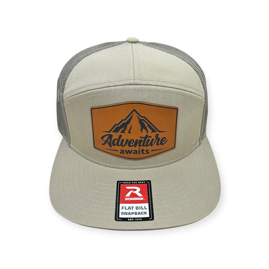 Front view of Adventure Awaits patch hat by Horizon Hat Co. in pale khaki/loden green showing adventure awaits patch with mountain artwork