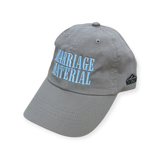 Angled view of Marriage Material embroidered cap by Horizon Hat Co. in gray/light blue lettering showing the bill and side panels