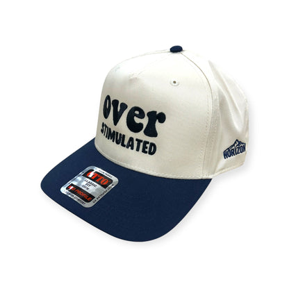 Angled view of the natural and navy Overstimulated embroidered cap