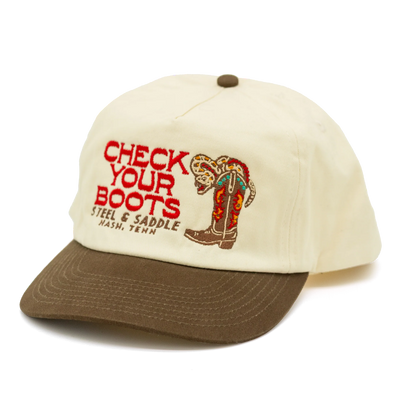 Steel & Saddle Rattler cap with a cream crown, brown bill, and Check Your Boots embroidery