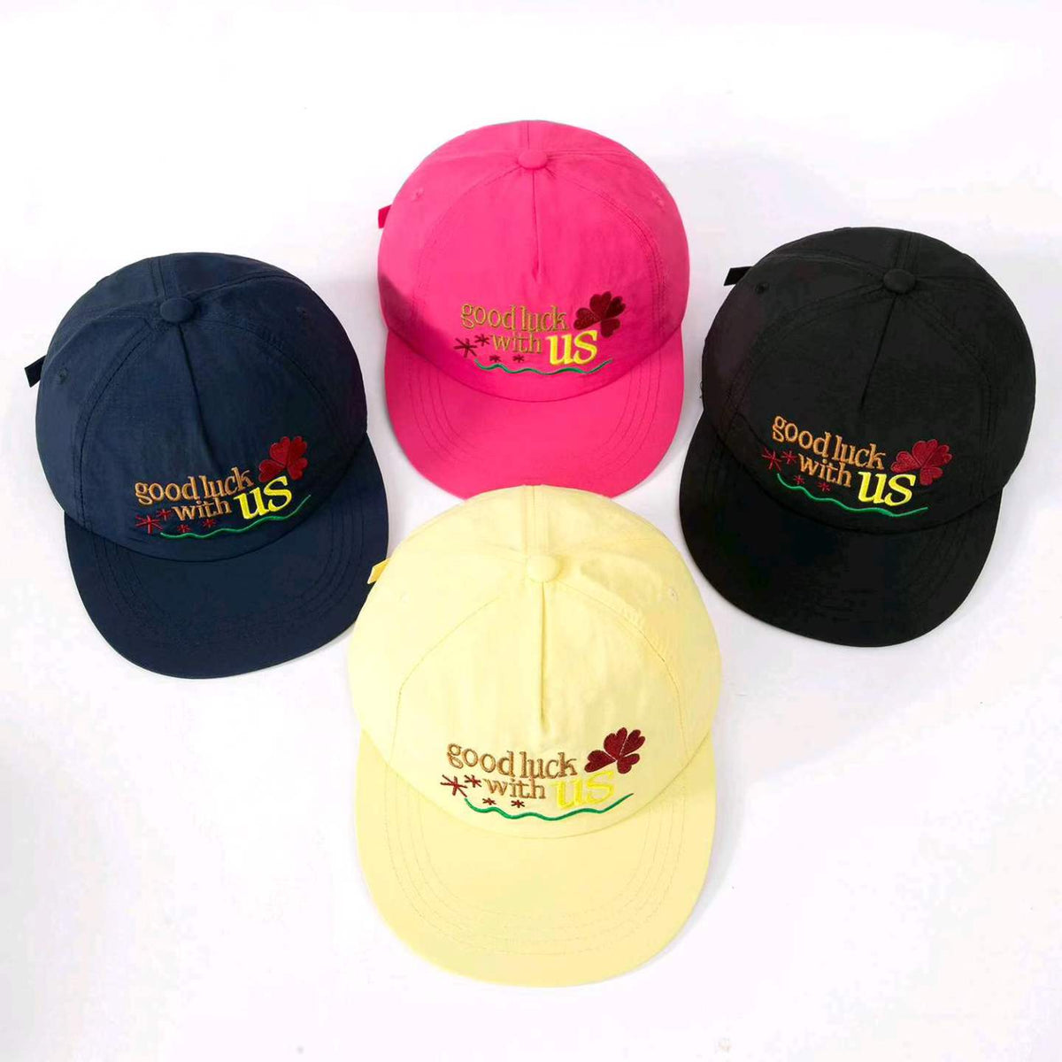 Four lucky clover embroidered baseball caps in blue pink black and yellow