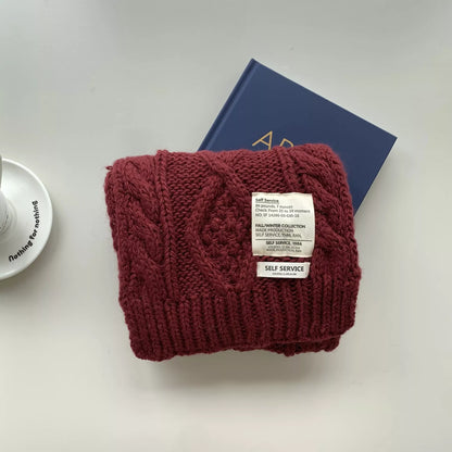 Unisex Chunky Cable Knit Scarf — burgundy cable knit scarf folded on printed pages