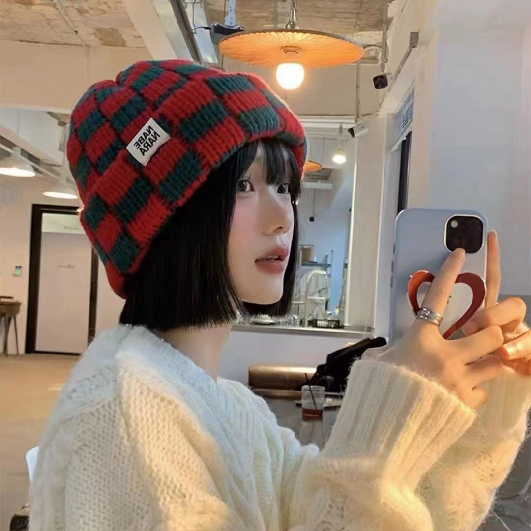 Side view of red and green checkerboard beanie worn with winter layers