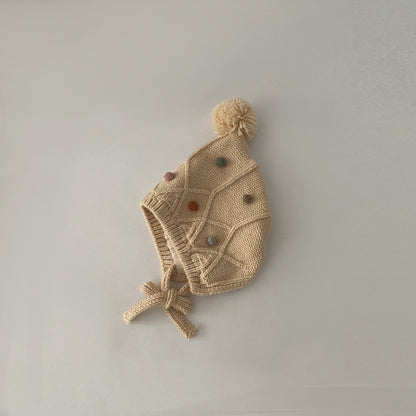 Beige pom pom earflap beanie with decorative accents