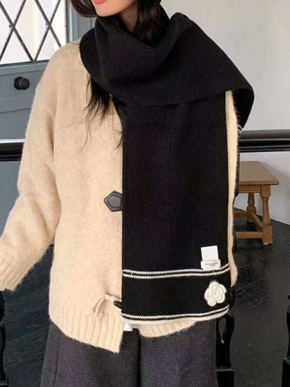 Women's Contrast Trim Knitted Scarf with Camellia Decor — camellia scarf draped long over a cream cardigan