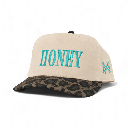 The Mad Hatter Company Honey Snapback, natural crown with a leopard-pattern bill and teal lettering